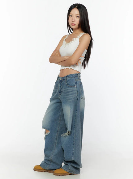 Lace Trim Tank CU526 White three-quarter side view on model with arms crossed, floral lace V-neckline, ribbed crop fit, styled with ripped wide-leg jeans