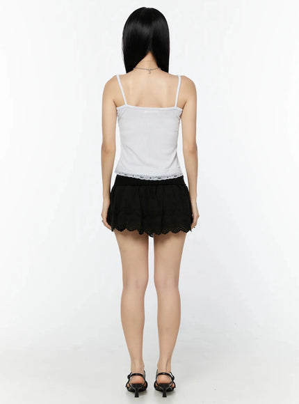 Lace Trim Tank Top IL516 White back shot on model standing, thin spaghetti straps, lace hem trim at back, styled with black eyelet mini skirt and sandals