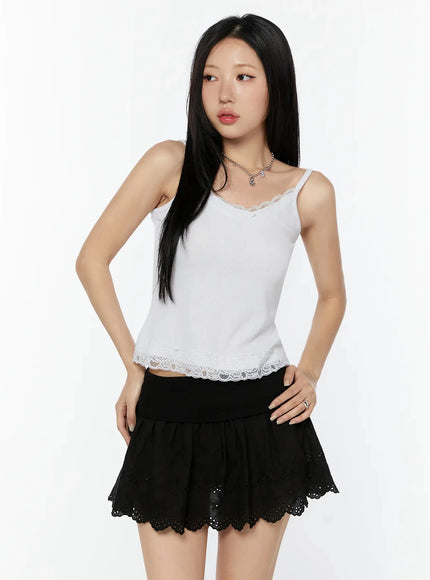 Lace Trim Tank Top IL516 White front shot on model looking to side, hand on hip, lace V-neckline and lace hem trim, styled with black eyelet mini skirt