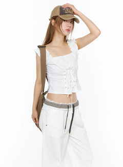 LEWKIN Lace-Up Corset Blouse Top CL502 White S/M angled front shot on model wearing cap and crossbody bag with ruched ruffle straps and lace-up corset detail
