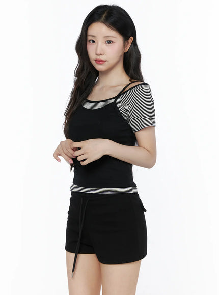 Layered Cami Striped Tee IU525 Black model angled front shot hands clasped showing black ribbed cami over black and white striped raglan tee with black shorts