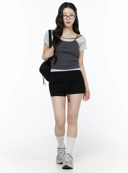 Layered Cami Striped Tee IU525 Dark gray model front shot carrying shoulder bag smiling styled with glasses black shorts white socks and sneakers full-body