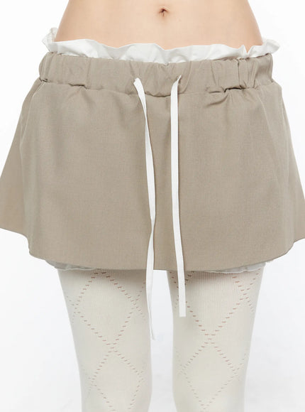 Layered Low-Rise Mini Skirt CL523 Beige close-up front detail shot of paperbag elastic waistband white ribbon drawstring and woven fabric texture