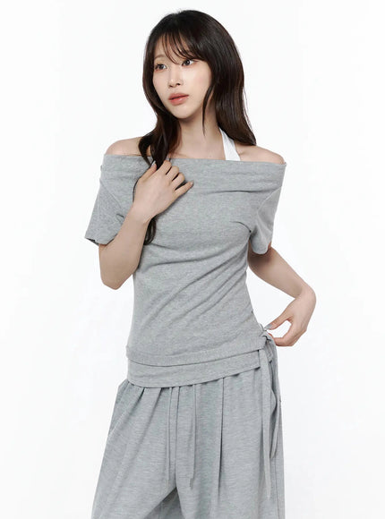 Layered Off-Shoulder Halter Top IL506 Gray three-quarter front shot on model with hand raised to collar, showing off-shoulder drape and side tie hem detail