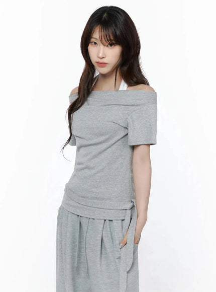 Layered Off-Shoulder Halter Top IL506 Gray three-quarter side shot on model looking at camera, showing asymmetric shoulder fold and layered halter strap