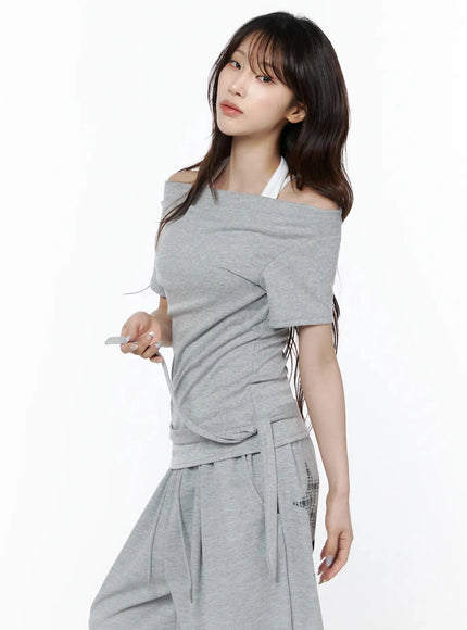 Layered Off-Shoulder Halter Top IL506 Gray side-angle shot on model holding waist tie, showing ruched body, off-shoulder fold, and star-print wide-leg pants