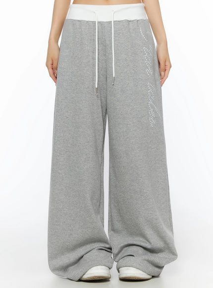 LEWKIN Lettering Contrast Waist Sweatpants IL515 Gray front close-up on model showing white contrast waistband, white drawstring, and star-dot graphic print on wide-leg fleece pants