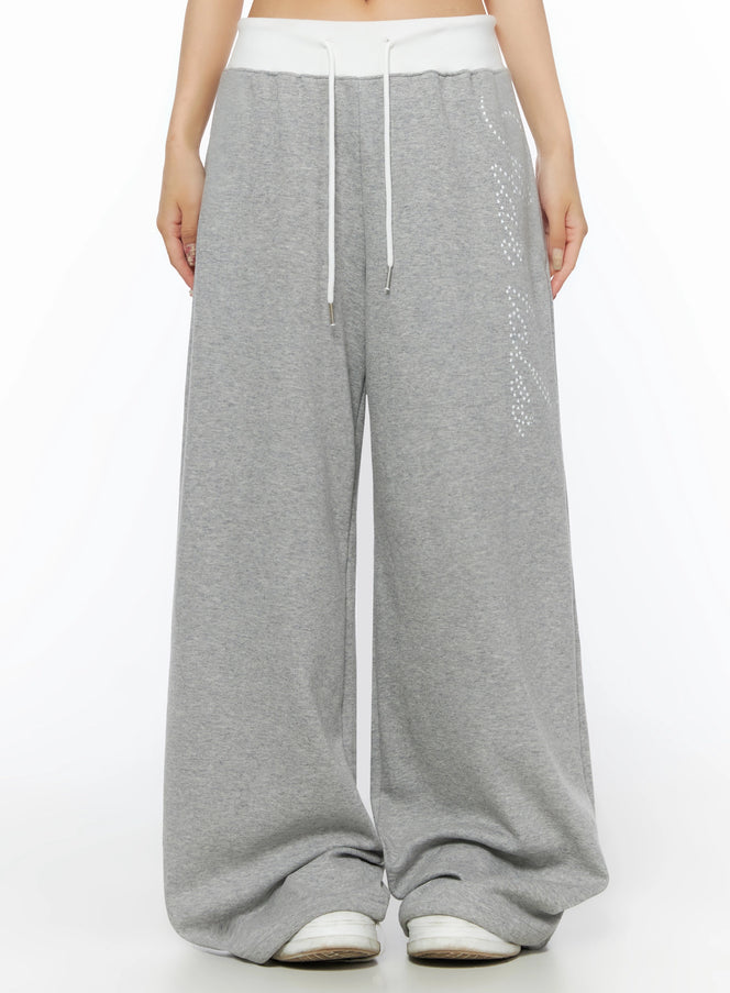 LEWKIN Lettering Contrast Waist Sweatpants IL515 Gray front close-up on model showing white contrast waistband, white drawstring, and star-dot graphic print on wide-leg fleece pants