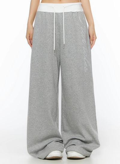 LEWKIN Lettering Contrast Waist Sweatpants IL515 Gray front close-up on model showing white contrast waistband, white drawstring, and star-dot graphic print on wide-leg fleece pants