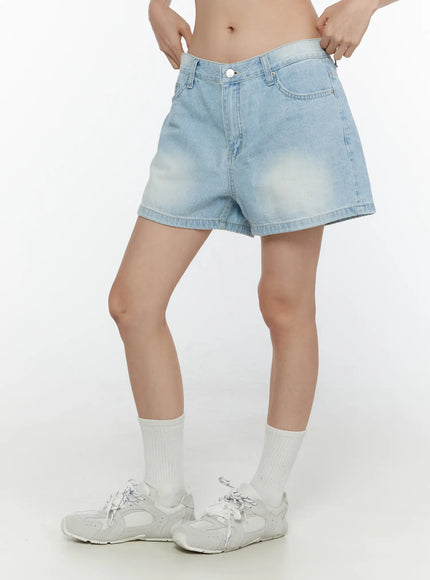 Light Washed Denim Shorts CL520 Light blue side shot on model hands adjusting waist paired with white socks and sneakers showing silhouette