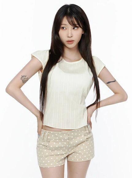 Linen Summer Blouse IL506 cream front model shot hands on hips, vertical stripe texture, cap sleeves, styled with beige polka dot mini shorts