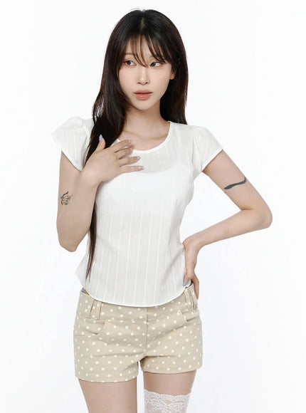 Linen Summer Blouse IL506 White front model shot hand on chest pose, cap sleeves, vertical stripe texture, styled with polka dot mini shorts and lace socks