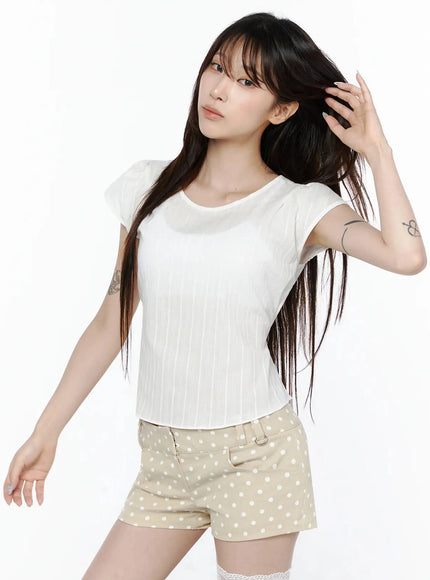 Linen Summer Blouse IL506 White front model shot dynamic pose hand in hair, vertical stripe cap sleeve crop top styled with beige polka dot shorts