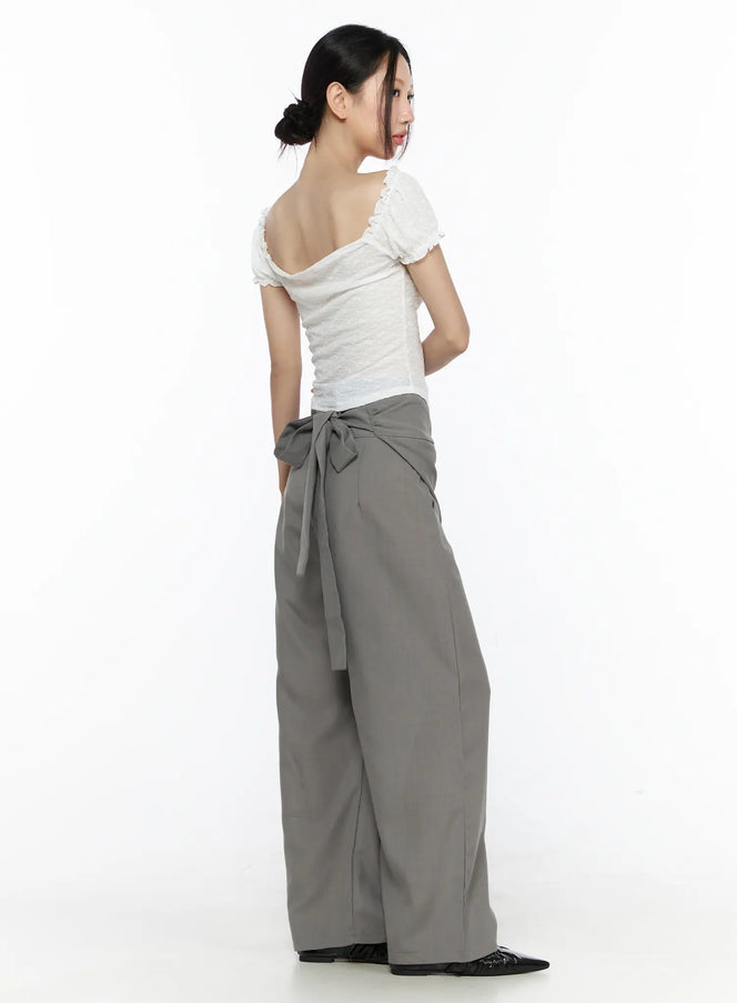 Linen Wrap Slacks CL527 Beige back view on model revealing tie bow detail at waist wide-leg cut styled with white lace puff-sleeve top and black flats