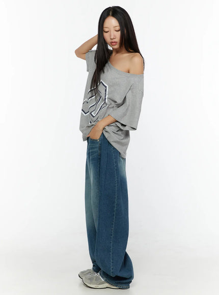 Loose Fit Oversized Tee CU526 Gray full-body side shot on model looking down with hand raised to hair, off-shoulder drape showing oversized silhouette, paired with wide-leg jeans