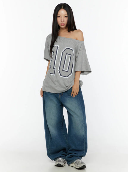 Loose Fit Oversized Tee CU526 Gray full-body front shot on model standing straight, off-shoulder neckline with navy number 10 distressed print, styled with baggy jeans and sneakers