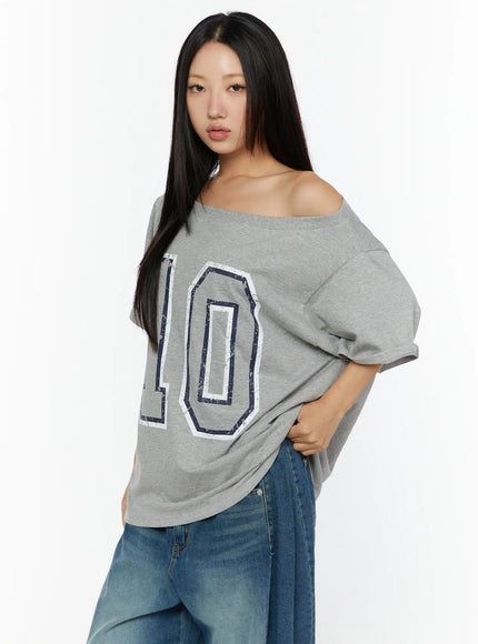 Loose Fit Oversized Tee CU526 Gray three-quarter front shot on model hand on hip, close view of navy and white distressed number 10 print on off-shoulder oversized cotton tee