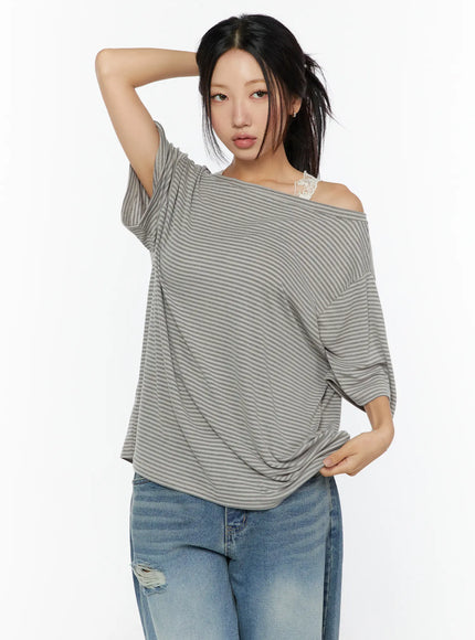 Loose Fit Striped Top CU526 Beige half-bust front shot on model with arm raised behind head highlighting draped shoulder and stripe pattern