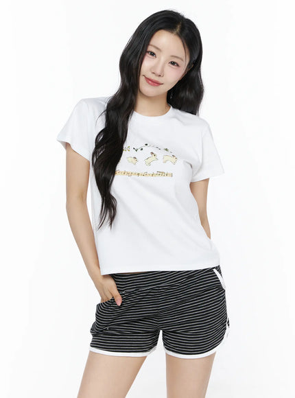 Lovely Bunny Graphic Tee IU525 White front shot on model smiling hand in pocket, leaping bunny and music score graphic on relaxed cropped tee