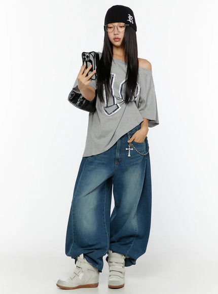 Lovi Washed Wide Leg Jeans CU526 Blue full-body styling shot on model wearing beanie and graphic tee, holding phone with cross chain accessory on pocket