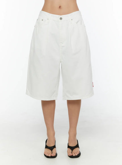 Low-Rise Cotton Shorts CU529 White front view on model showing low-rise waistband pleated wide leg red side label and black wedge thong sandals