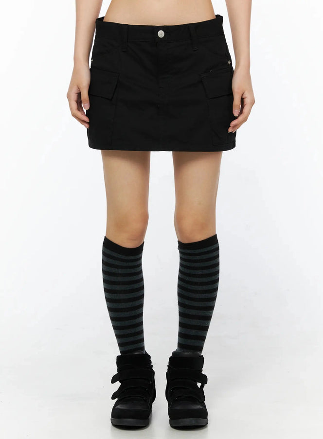 LEWKIN Low Rise Crinkle Cargo Skort IL509 Black front shot on model cropped at waist showing cargo pockets silver button waistband striped knee socks black sneakers