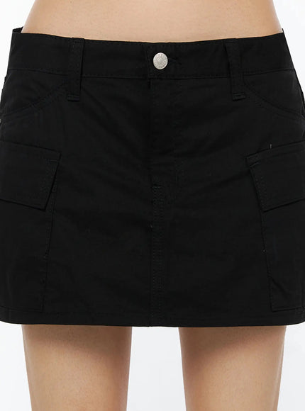 Low Rise Crinkle Cargo Skort IL509 Black close-up front detail shot on model showing dual cargo pockets silver button waistband stitching crinkle cotton texture