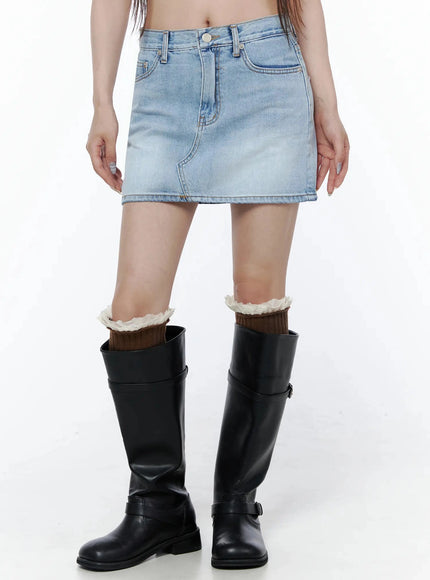 Low-Rise Denim Mini Skirt IL502 Light blue front waist-down shot on model with knee-high black boots, showing faded wash and topstitching detail