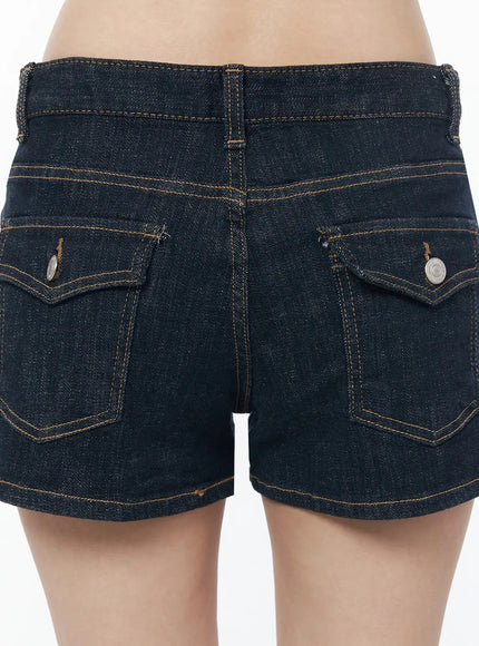 Low-Rise No-Fade Denim Shorts IU525 Dark blue close-up back detail showing double flap pockets, silver coin buttons, and amber contrast stitching on raw denim