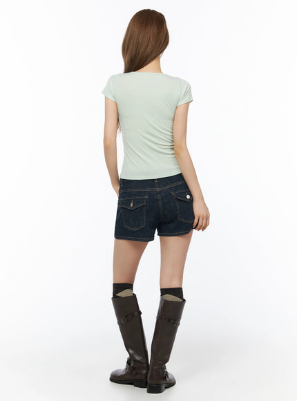 Low-Rise No-Fade Denim Shorts IU525 Dark blue back full-body shot on model in mint top showing flap pockets with silver buttons and contrast gold stitching