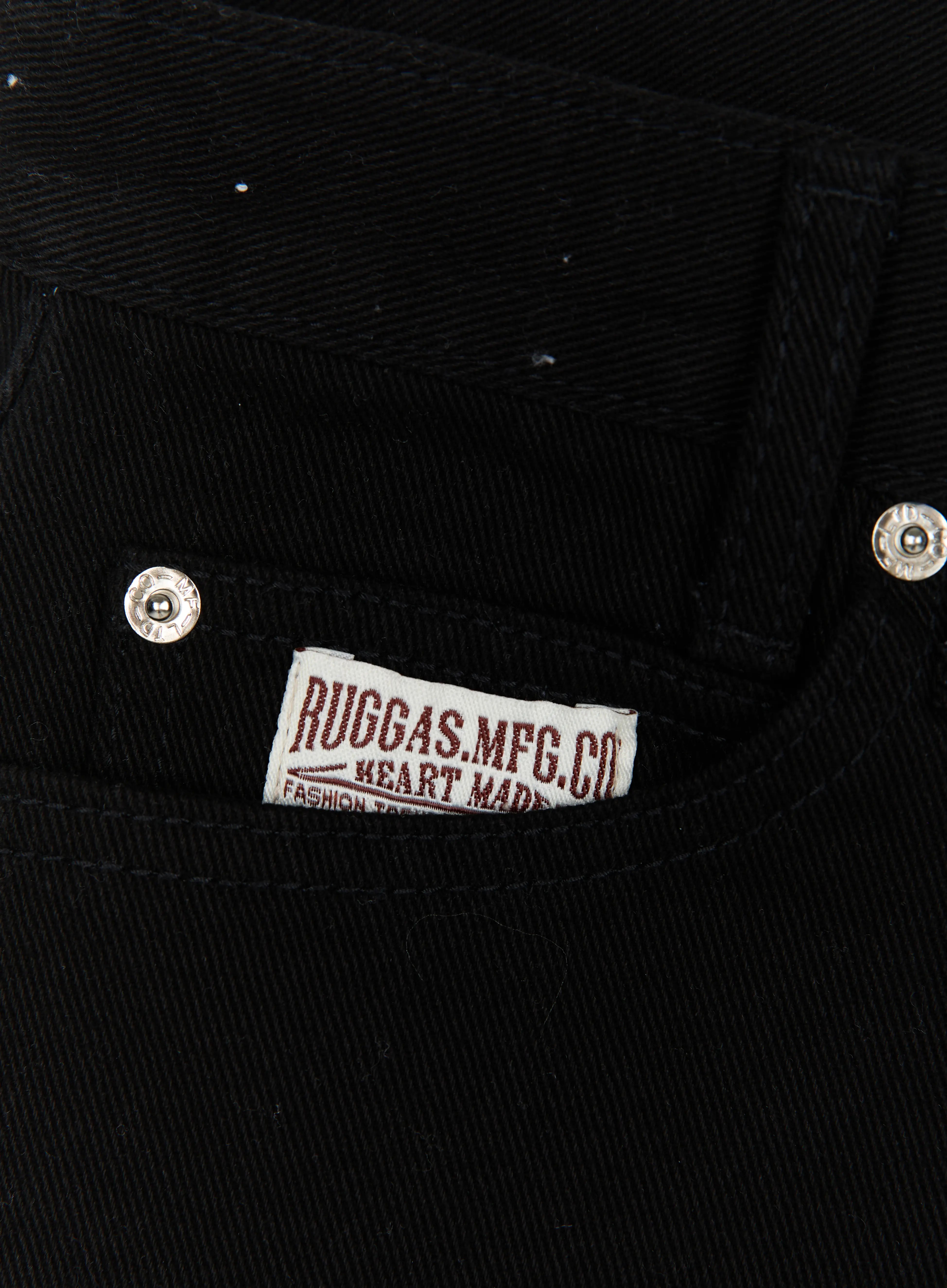 Low Rise Shorts IL521 Black close-up detail of RUGGAS.MFG.CO woven label on front pocket with silver rivet hardware on black twill denim fabric