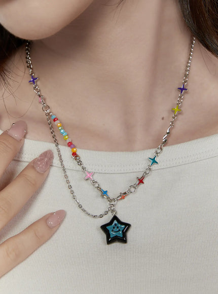 Lyra Star Crystal Necklace IL517 multicolor front view on model wearing white top, layered styling with colorful bead strand and multi-star enamel chain with black smiley star pendant