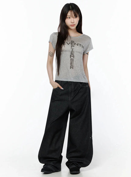 Maelani Rivet Wide Balloon Jeans IL502 Black full-body front shot on model with hands in pockets, paired with gray graphic crop tee, relaxed standing pose