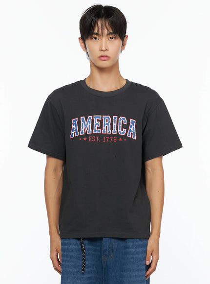 Men's America Print T-Shirt IL515 Dark gray front close-up crop shot on male model showing AMERICA EST. 1776 star-filled collegiate print detail on chest