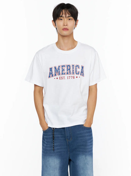 Men's America Print T-Shirt IL515 White front cropped shot on male model highlighting AMERICA EST. 1776 blue star-print arched collegiate graphic on white cotton