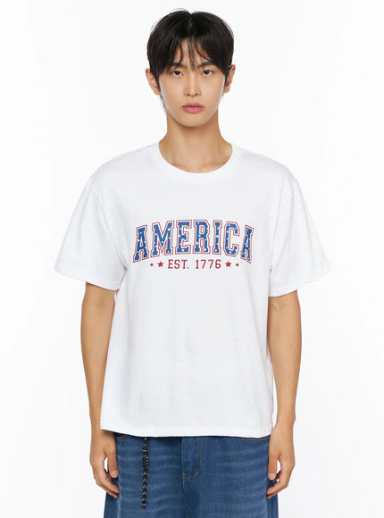 Men's America Print T-Shirt IL515 White front close-up crop shot on male model showing AMERICA EST. 1776 blue and red star-pattern arched graphic on white cotton tee