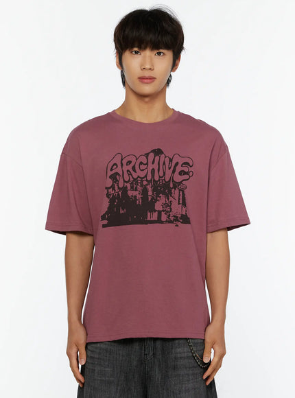 Men's Archive Graphic T-Shirt IL515 mauve close-up front crop view on model showcasing ARCHIVE graffiti bubble-letter cityscape chest graphic print detail