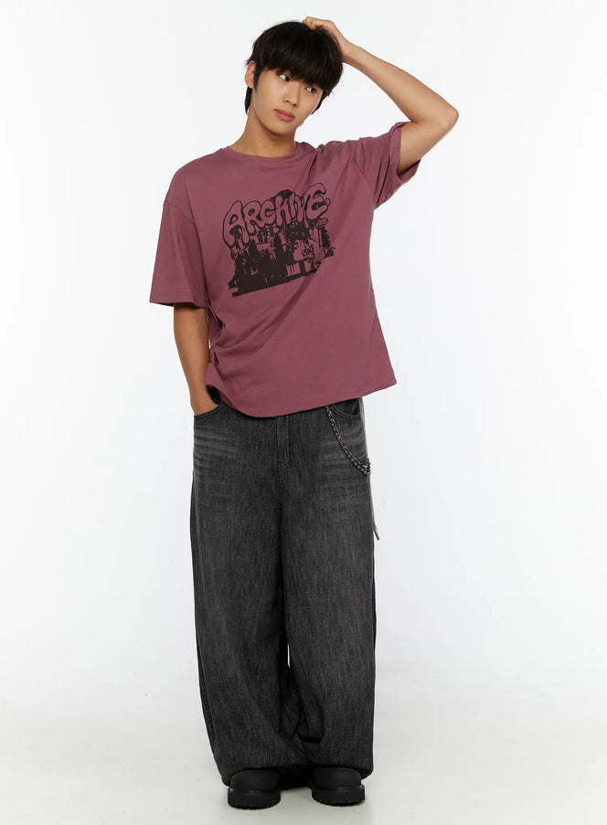 Men's Archive Graphic T-Shirt IL515 mauve full-body front view on model with hand raised to head styled with wide-leg gray denim and chain