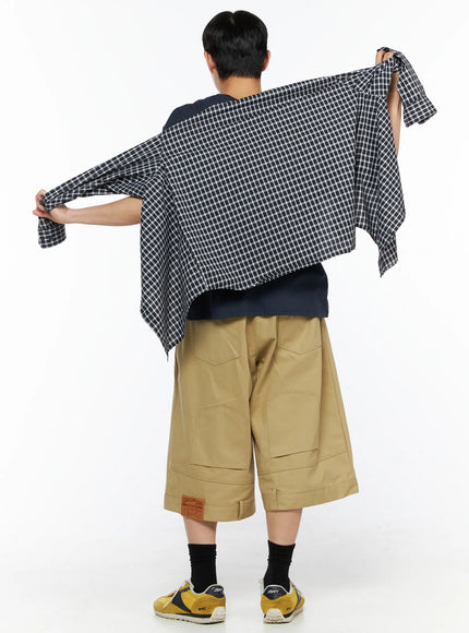 Men's Baggy Bermuda Shorts IL514 Beige back view on model holding up plaid shirt overhead, showing wide-leg cut and back patch pockets with leather label at hem