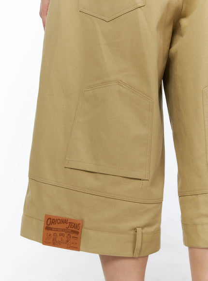 Men's Baggy Bermuda Shorts IL514 Beige close-up detail of angular stitched cargo pocket, leather Original Jeans woven patch label, and cuffed hem on cotton twill fabric