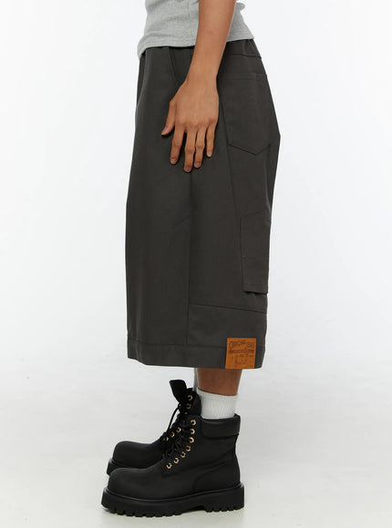 Men's Baggy Cargo Shorts (Dark Gray) IL515 Dark Gray side view on male model styled with striped long-sleeve top, black scarf, crossbody bag, and combat boots