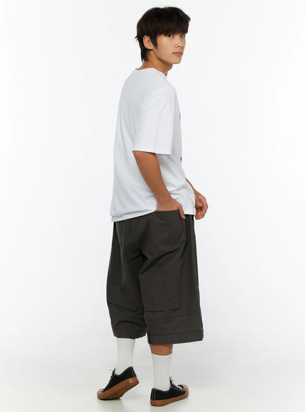 Men's Baggy Cargo Shorts (Dark Gray) IL515 Dark Gray three-quarter back view on male model styled with white graphic tee and canvas sneakers showing relaxed silhouette