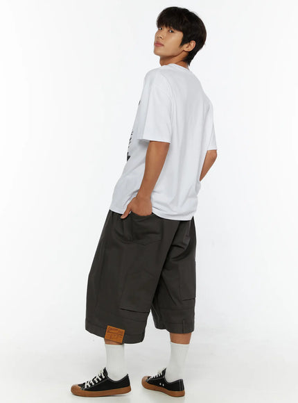 Men's Baggy Cargo Shorts (Dark Gray) IL515 Dark Gray back three-quarter view on male model styled with white graphic tee and canvas sneakers