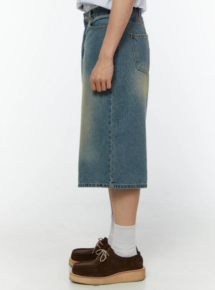 Men's Baggy Fit Jorts IU529 Blue side view on model showing knee-length hem, back pocket detail, and vintage yellow-tinted faded denim wash