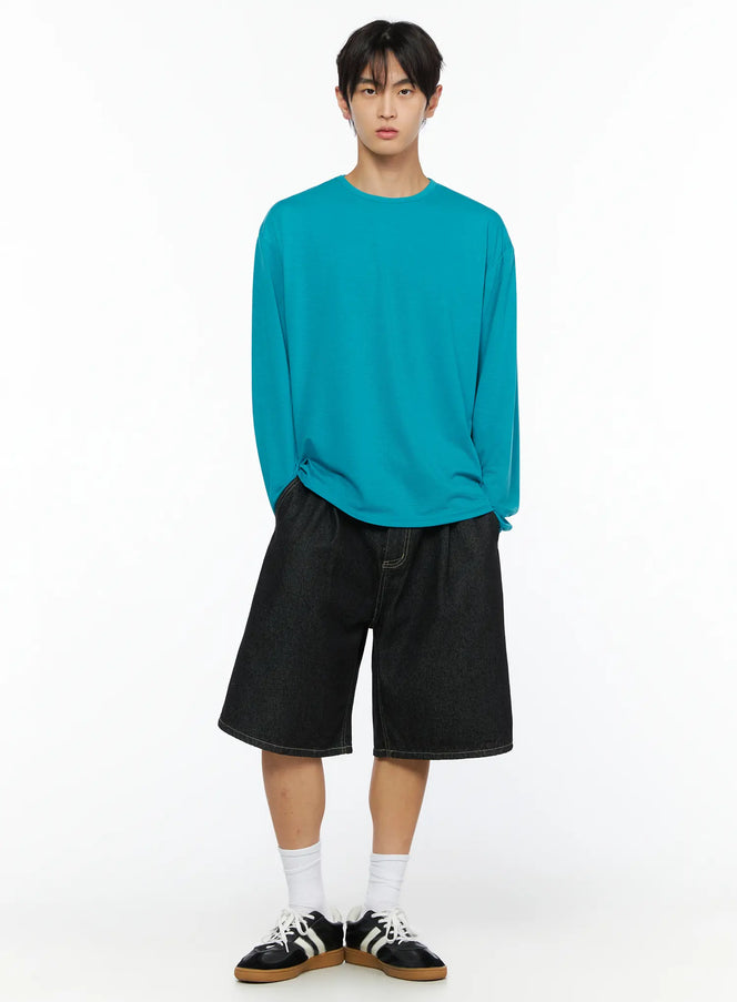 Men's Basic Long Sleeve T-Shirt IL528 Teal front shot on male model with hands in pockets styled with black denim shorts and sneakers
