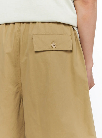 Men's Bermuda Shorts (Beige) IL514 beige close-up back detail shot showing button-flap back pocket and elastic waistband on male model