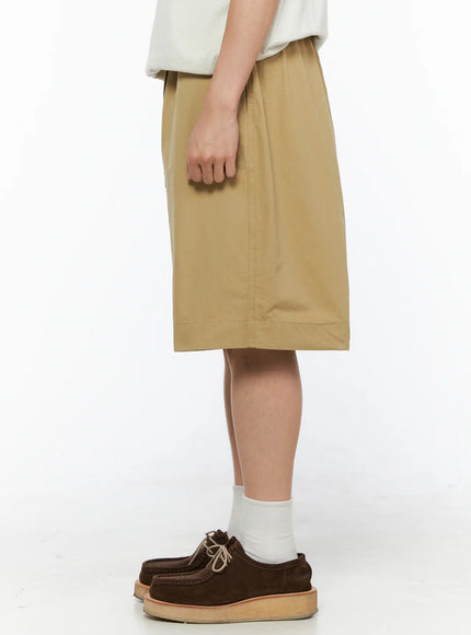 Men's Bermuda Shorts (Beige) IL514 beige side shot on male model showing clean side seam and knee-length hem with wide relaxed silhouette