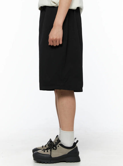 Men's Bermuda Shorts (Black) IL514 black side shot on model showing straight wide silhouette elastic waistband hem length and side seam detail