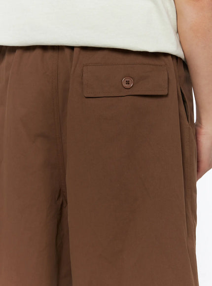 Men's Bermuda Shorts (Dark Brown) IL514 dark brown close-up detail of back pocket with tonal button and elastic waistband on male model