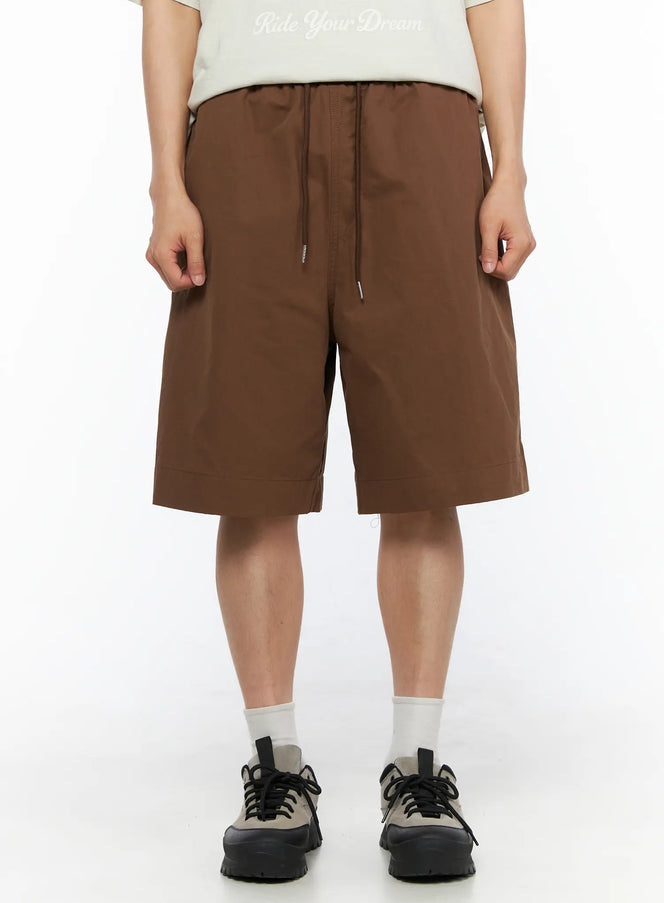 LEWKIN Men's Bermuda Shorts (Dark Brown) IL514 dark brown front view on male model standing straight styled with graphic tee and chunky sneakers